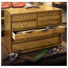 an old wooden tool box with drawers and tools in front of it on a workbench