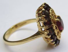 This ring looks so regal! The deep red garnets against the rich colored 18k gold compliment each other beautifully. Dating from the early 1900's-40's and hallmarked in the interior 750 and 176AAL. Has been tested to ensure the golds purity. Rings size is 6 1/2 and is ready to be worn and admired! The halo setting measures 11/16 by 7/16 of an inch. Stones are all held securely in place. Center garnet measures 6.12mm by 4.25mm. Some stones have light surface wear as to be expected with a ring of s Luxury Ruby Ring Marquise Cut For Formal Events, Luxury Ruby Marquise Cut Ring For Formal Occasions, Luxury Marquise Cut Ruby Ring For Formal Occasions, Vintage Multi-stone Ruby Ring In 14k Gold, Victorian Gold Cluster Ring With Gemstone, Elegant Garnet Ruby Ring Stamped 14k, Formal Multi-stone Marquise Ruby Ring, Formal Marquise Multi-stone Ruby Ring, Luxury Marquise Cut Yellow Gold Ruby Ring