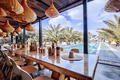 an outdoor dining area with tables and chairs next to a pool surrounded by palm trees