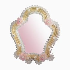 an ornate mirror with pink and gold trimmings on the edges, against a white background