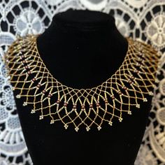 a black mannequin with gold and red beads on it's neckline