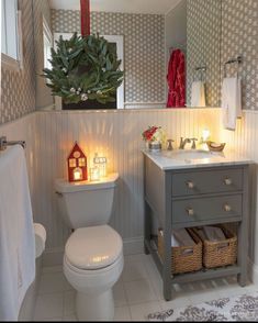 a white toilet sitting next to a sink in a bathroom under a christmas tree with lights on it