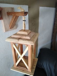 a small wooden lantern with rope hanging from it's top on a shelf next to a black leather chair