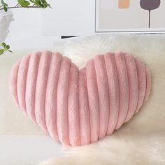 a pink heart shaped pillow sitting on top of a white couch