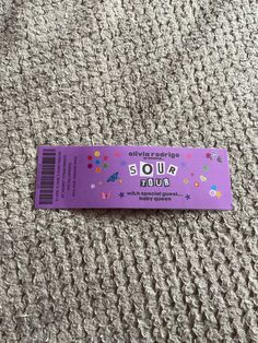 a purple ticket sitting on top of a carpet covered in lots of confetti