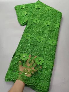 the green lace is being sewn on by someone's hand with their fingers