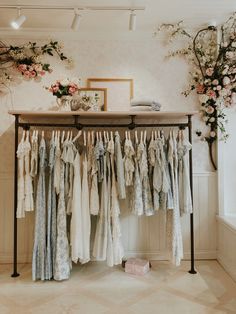 an old fashion clothing rack with clothes hanging from it's rails and flowers on the wall