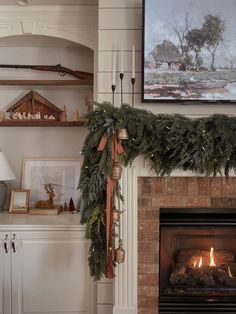 the fireplace is decorated for christmas with greenery and candles on it's mantle