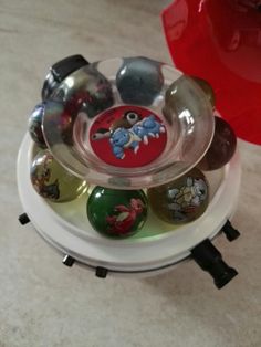 an assortment of glass balls in a bowl on top of a stand with magnets