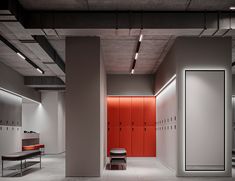 an empty room with lockers and benches on the floor in front of red doors