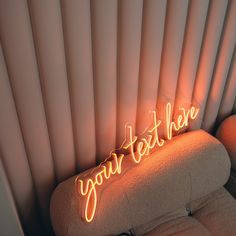 a neon sign that reads, your text here on the back of a couch in a room