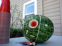 a large watermelon sitting on top of a table in front of a house