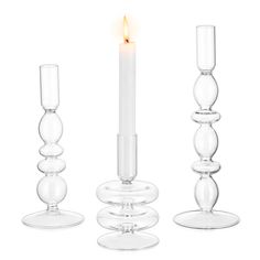 three clear candlesticks with one lit candle in the middle and two on each side