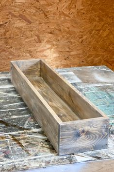 a wooden box sitting on top of a table next to some wood planks and plywood