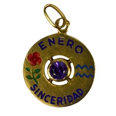 An 18 karat yellow gold charm pendant designed as a gold disc with enamel inlay of 'ENERO SINCERIDAD' (January Sincerity) with the zodiac symbol for Aquarius and a carnation (symbolising devotion, loyalty and love) in enamel, and set to the centre with a purple amethyst. Stamped with the owl mark for French import and 18 karat gold. Dimensions: 2 x 1.6 x 0.25 cm (not including jump ring) Weight: 1.40 grams Symbolic Engraved Pendant Charms, Symbolic Engraved Round Pendant Charms, Gift Coin Pendant Charm, Engraved Round Pendant Jewelry As Souvenir, Engraved Round Pendant Jewelry For Souvenir, Yellow Gold Gemstone Charms For Gift, Yellow Gold Enamel Charms For Gift, Engraved Enamel Jewelry For Anniversary, Symbolic Yellow Gold Jewelry With Birthstone