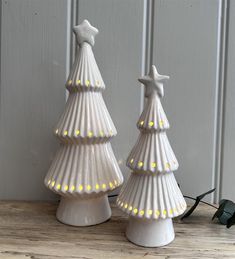 two white ceramic christmas trees with lights on them