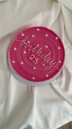 a pink cake with hearts on it sitting on a white tablecloth covered sheet that says happy valentine's day