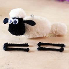 a stuffed sheep laying on its side next to some black and white hair clips in front of it