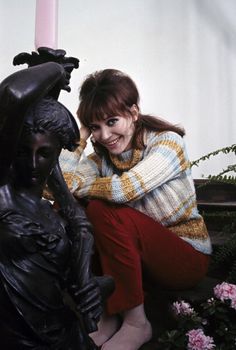 a woman sitting on the ground next to a statue with a candle in her hand