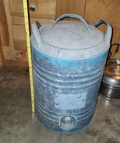 an old metal container with a measuring tape on the floor next to some pots and pans