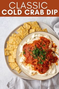 a white plate topped with cheese and sauce next to crackers