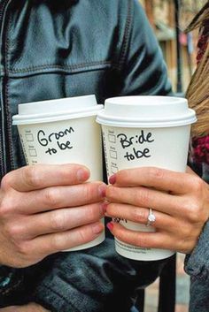 two people holding coffee cups with writing on them