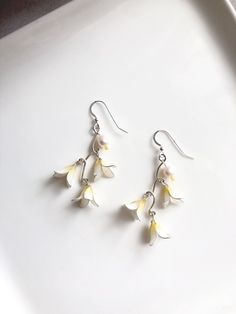 Three little white flowers hanging on a branch in silver color. Cultured freshwater pearls were added on the branch. A pair of cute and elegant image earrings. More about her: Resin: Japanese resin in white and yellow color. Wire for flowers: 0.45mm silver plated brass wire  Branches: 1.02mm sterling silver filled brass wire. Closure: 925 sterling silver fishhook ear wire/Brass ear clip in silver color  Pearls: 8mm cultured freshwater pearls in white color. Care: To enlarge the life of our jewelry please do not press, do not crush, do not pull the pair and store it in the bag provided. White Sterling Silver Dangle Flower Earrings, Delicate Pearl White Flower Pearl Earrings, Delicate Flower-shaped Pearl Earrings With Ear Wire, Delicate Flower Shaped Pearl Earrings With Ear Wire, Delicate White Sterling Silver Earrings, Dainty White Sterling Silver Flower Earrings, Dainty White Birth Flower Earrings, Silver Flower Pearl Earrings With Flower Charm, Handmade White Flower Pearl Earrings