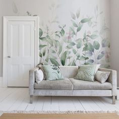 a couch sitting in front of a wall with leaves painted on it's side