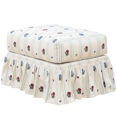 a white ottoman with red and blue flowers on the bottom, sitting on top of it