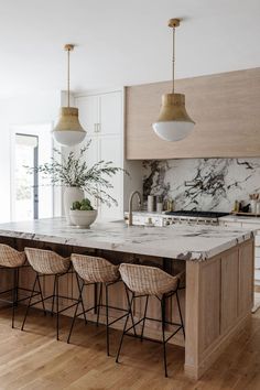 a kitchen with marble counter tops and stools next to an island in the middle