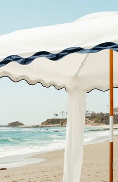 an open umbrella on the beach with water in the back ground and sand behind it