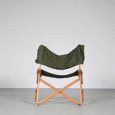 a green folding chair sitting on top of a cement floor next to a white wall