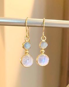 "Moonstone (10mm) and Aquamarine (6.5) set in 22 karat gold.  Stunning pair of drop earrings with the soft color of light blue aquamarine and the billowy moon-like sheen of the moonstone cradled in 22 karat yellow gold. The earring dangle 1.5\" from the earlobe." Gold And Blue Earrings, Yellow Gold Moonstone Dangle Earrings, Round Gold Moonstone Earrings, Blue Moonstone Round Earrings, Elegant Blue Moonstone Earrings, Formal Round Moonstone Earrings, Elegant Blue Moon Shaped Earrings, Moonstone Round Yellow Gold Earrings, Moonstone Yellow Gold Round Earrings