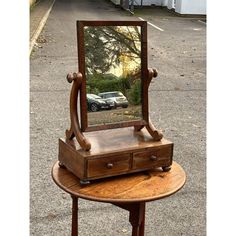 a wooden table with a mirror on top of it and a car in the background