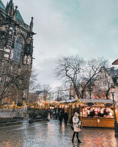 people are walking around in the rain near an old building with christmas lights on it