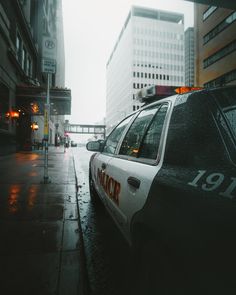 a police car is parked on the side of the street in the rain with its lights on