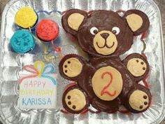 a birthday cake shaped like a teddy bear with two balloons and a happy 2nd birthday sign