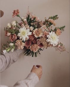 a woman holding a bouquet of flowers in her hand while another person places it on the wall