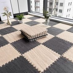 a living room with a checkered rug on the floor and two vases filled with flowers