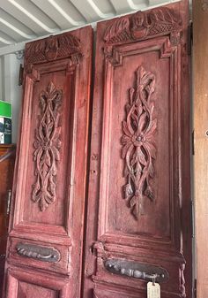 two wooden doors with carvings on them in a store or office area, one has a price tag hanging from the door