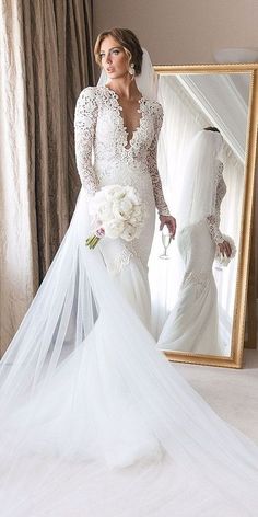 a woman is standing in front of a mirror wearing a wedding dress