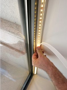 a hand is holding the handle to an illuminated door