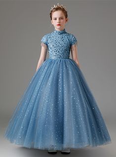 Presenting a dress that embodies elegance and charm for your flower girl. This beautiful blue dress features a bodice embellished with intricate floral appliques and sequins, adding a layer of sophistication and luxury. The high neckline and cap sleeves, decorated with sparkling beads, bring a whimsical and enchanting feel to the dress. The skirt, crafted from multiple layers of tulle and dotted with shimmering sequins, creates a voluminous and fairy-tale-like silhouette perfect for twirling and Scoop Wedding Dress, Champagne Ball Gown, Beading Wedding Dress, Sequin Flower Girl Dress, Wedding Dress Buttons, Flower Girl Dresses Blue, Short Sleeve Wedding Dress, Green Tulle, Wedding Dress Champagne