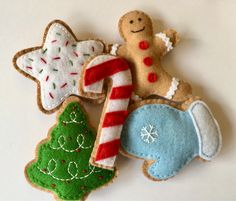 four decorated cookies on a white surface with candy cane, gingerbread and christmas tree