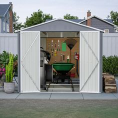 an outdoor storage shed with its doors open and tools on the table in front of it