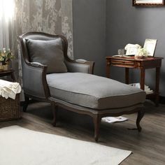 a chair and ottoman in a room with gray walls, wood flooring and white rugs