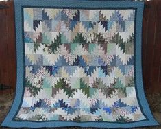 a blue and white quilt hanging from a wooden fence