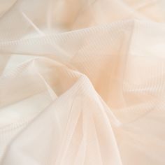 ABOUT THIS ITEM: Beautiful draping soft tulle (not a crisp net) Ideal for layers of rusching in bridal & eveningwear On trend shade of very pale peach pink. We stock this colour in our 300cm wide bridal tulle as 'Champagne'. Full width 150cm, 100% Polyester The listing price is for 1 metre. If you buy multiple purchases of this listing it will be sent in one full length. This same fabric also comes in 9 other colours. WANT TO SEE A SAMPLE BEFORE YOU BUY? We know that its important to get a g Elegant Cream Sheer Tulle Fabric, Cream Embroidered Tulle Fabric, Sheer Cream Tulle Fabric, Elegant Cream Tulle Veil, Elegant Stretch Tulle Fabric For Wedding, Light Peach Color, Pale Peach, Soft Tulle, Light Peach