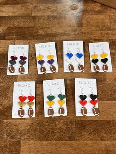 six pairs of heart shaped earrings are displayed on the floor in front of a box