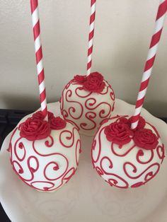 three red and white decorated cake pops on a plate